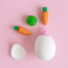 Bunny hatching from eggshell and vegetables abstract on rose.