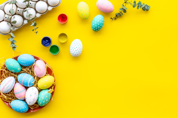 Colorful Easter eggs and paint for celebration on yellow background top view mock up