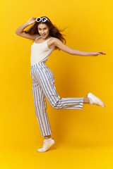 Fototapeta na wymiar Fun, joy, positive emotions and people concept. Vertical full length picture of emotioanl funny adorable cute teenage girl in stylish summer clothes and accessories posing in studio, dancing, smiling