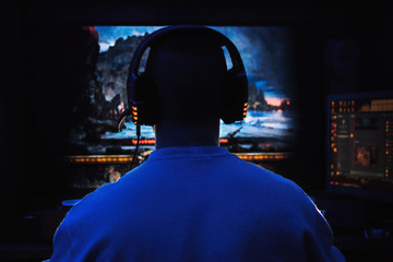 Men wearing headphones playing video games late at night © Катя Датунова