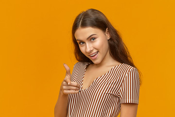 Cunning gorgeous young Caucasian woman dressed in striped top looking at camera with excited smile,...