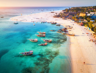 Vue aérienne des bateaux de pêche sur la côte de la mer tropicale avec plage de sable au coucher du soleil. Vacances d& 39 été sur l& 39 océan Indien, Zanzibar, Afrique. Paysage avec bateau, bâtiments, eau bleue transparente. Vue de dessus