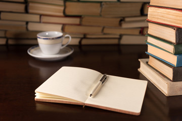 open notebook and cup on the background of books