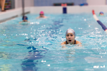 Swimmer young girl breathing performing the butterfly stroke in swimming pool, copy space