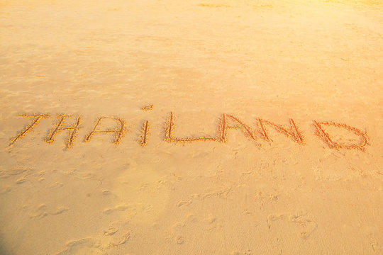 The inscription "Thailand" on the sand. Sunset light Footprints