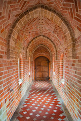 Wooden ancient door at the end of brick corridor