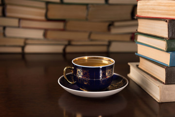cup of tea and many books on a wooden table