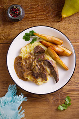 Liver with pears and cream and wine onion sause on mashed potato. overhead, vertical