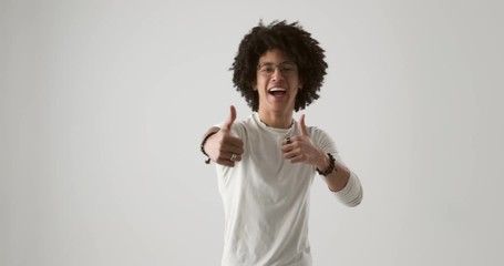 Young man with curly hair giving thumbs up gesture while dancing