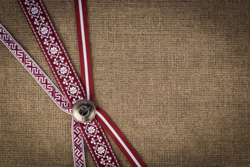 National ribbons fastened with a latvian brooch Sakta - obrazy, fototapety, plakaty