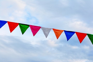 Colored triangular flags on blue sky background © Sanja