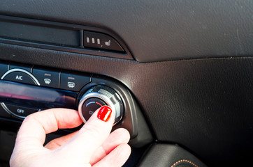 Female hand regulates climate control in car.
