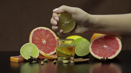 Woman squeezes juice from lemon into a glass cup with alcohol cocktail