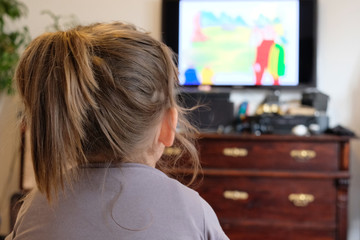 Small girl is watching a comic on TV