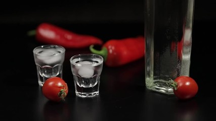 Cherry tomato roll up to two cups of vodka. Black background