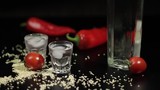 Sparse sesame seeds to two cups of vodka near bottel with vodka