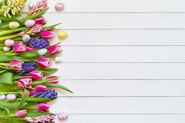 Easter background. Spring flowers and decorative Easter eggs on white background. Copy space, top view.