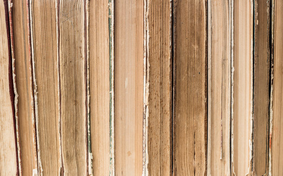 Old worn brown books in a row, light brown background.