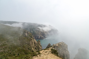 Cape Roca (Cabo da Roca) cliffs in fog. The rocks are obscured by clouds or fog. Cape Roca is most western part of Europe, Portugal.