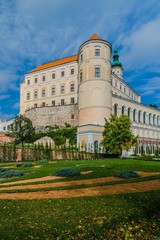 Fototapeta na wymiar Mikulov, Czech Republic / South Moravia - October 15 2016: Mikulov castle with yellow and white facade standing on a rock, green vegetation in a garden, sandy foot path, vertical image, sunny day