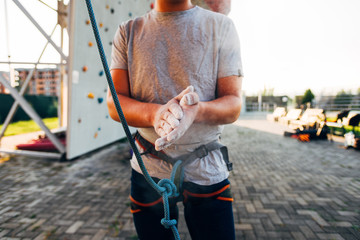 Young man wearing belay and sprinkling hands with talc