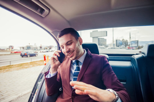 Handsome young businessman on phone call, sitting in elegant car