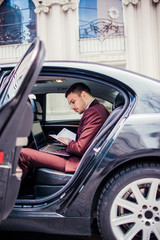 Fototapeta na wymiar Man in suit reading his notebook in the car