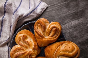 Heart-shaped bun with powdered sugar and cinnamon on a wooden background in a rustic style . Selective focus.