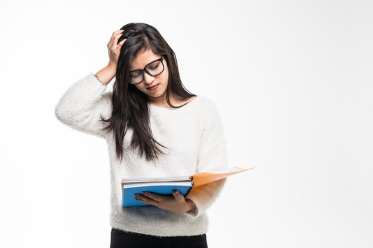 Portrait of attractive asian indian student woman standing holding reading a book with upset mood over white background. Education test exam thinking concept