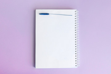 Top view notepad and flowers on desktop. For the concept of a wedding or female planner. Lilac background color of lavender