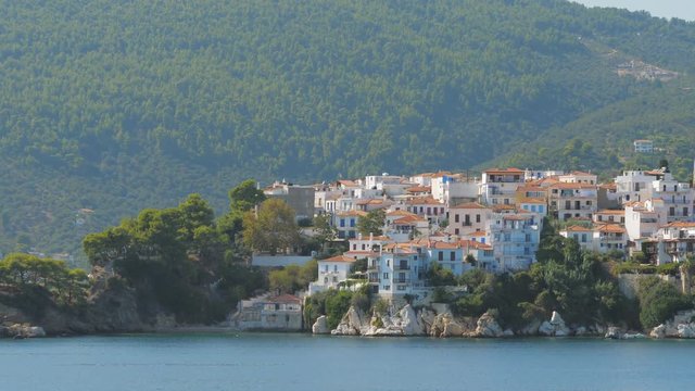 Passing near Skiathos harbor and green wooded island, sailing on blue sea