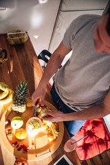 Vegan man in his 20's has a morning preparation of a smoothie while looking at a recipe on his tablet.