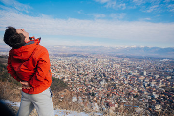 Strong male in his 20s stretching in the morning at winter while looking at his hometown in the valley..