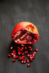Ripe pomegranate berries in a bowl, on the black wooden, close up on 