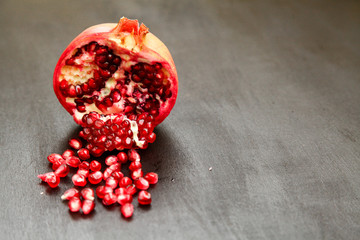 Ripe pomegranate berries in a bowl, on the black wooden, close up on 