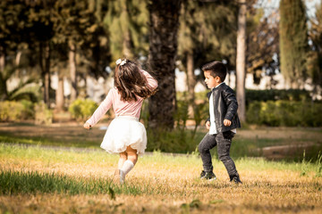 Naklejka na ściany i meble Children in park. Boy and girl playing and running