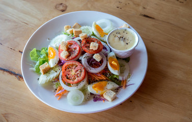 Fresh salad with vegetables tomatoes, cucumbers, lettuce, salad leaves and eggs on grey background top view and copy space. Vegetarian food. Healthy food and diet concept. 
