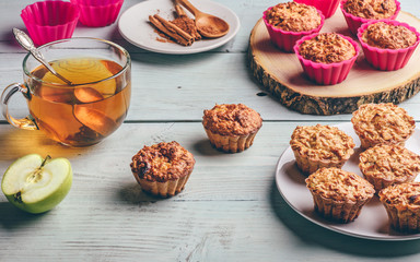 Cooked muffins with apple and cup of tea.