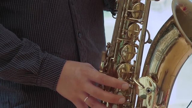 Saxophonist plays on saxophone. Close up