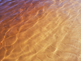 Abstract golden texture of ripples on the crystal water