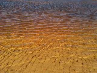 Abstract golden texture of ripples on the crystal water