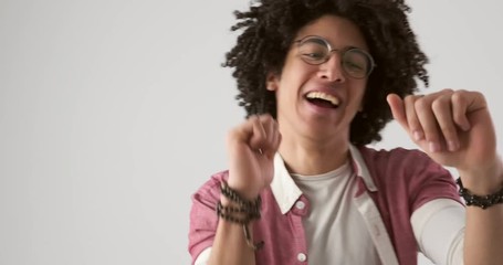 Happy young man with curly hair dancing over white background