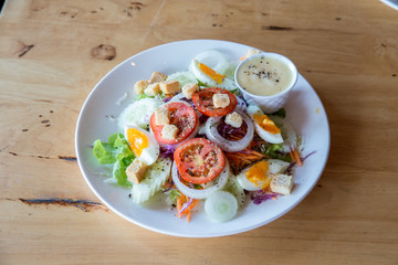 Fresh salad with vegetables tomatoes, cucumbers, lettuce, salad leaves and eggs on grey background top view and copy space. Vegetarian food. Healthy food and diet concept. 