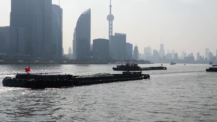 shanghai bund viewed from ferry ship, skyscrapers and landmarks with blue sky background, cargo ships sailing on Huangpu river, slow motion.