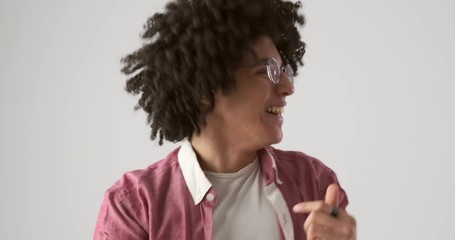 Excited young man with curly hair dancing over white background