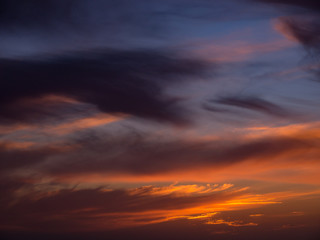 Wide angle view of dark dramatic clouds in sky at sunset with blue orange gradient