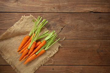 Fresh baby carrots on wooden cutting board and wooden background