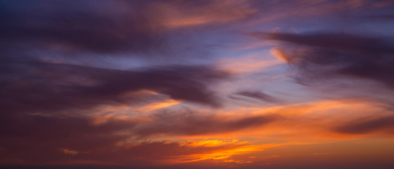 Wide angle view of dark dramatic clouds in sky at sunset with blue orange gradient