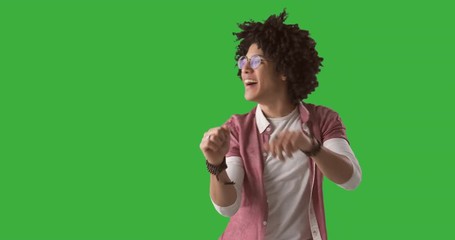 Happy young man with curly hair dancing on green screen