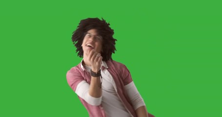 Excited man with curly hair dancing over green background